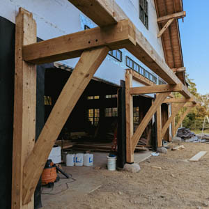 Structural timber framing for a 45-foot garage eyebrow roof with visible diagonal braces and stone footings.
