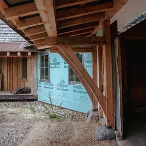Low angle view of timber rafters and the underside of a rusty corrugated metal eyebrow roof on a garage.