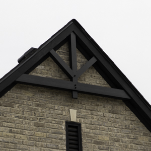 Hand-cut mortise and tenon joinery on a timber truss in front of brick wall.